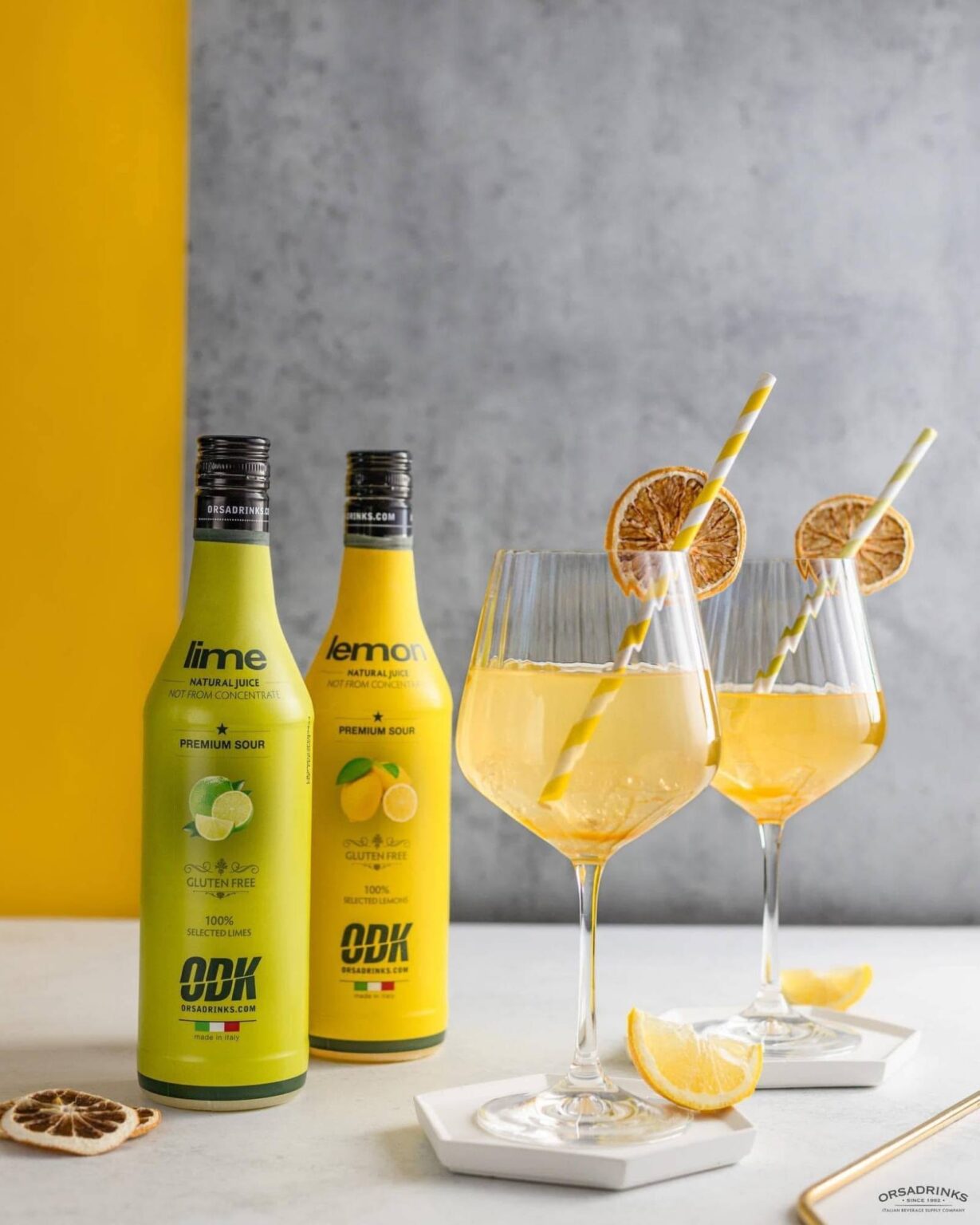 ODK lime and lemon premium sour bottles beside two citrus cocktails