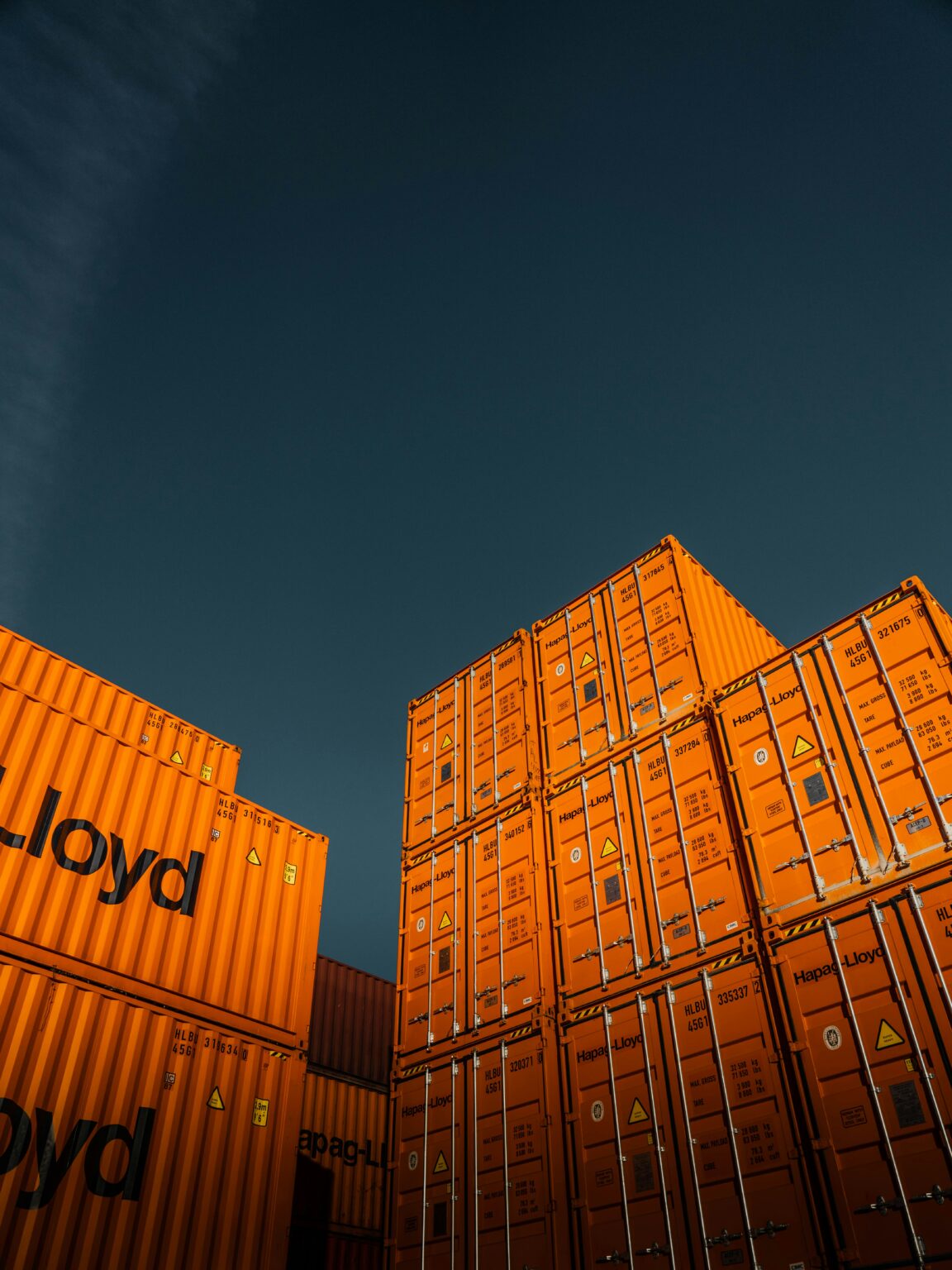 Stacked orange shipping containers against a dark sky