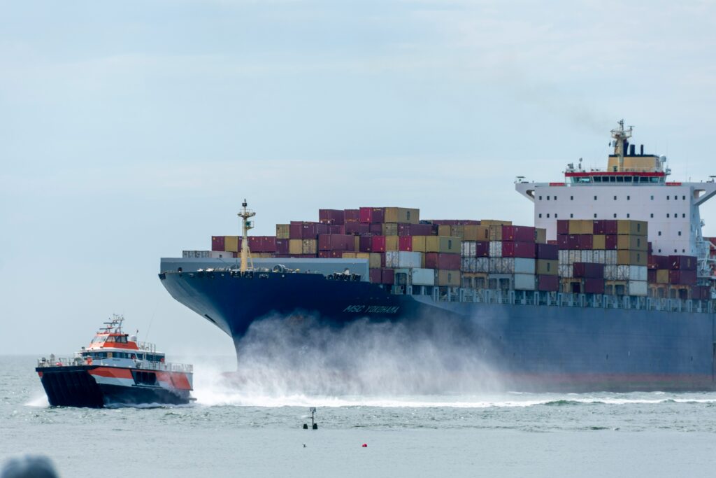 Container ship arriving in port with a pilot boat alongside